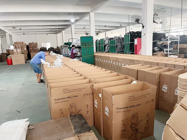 Workers packing ergonomic office chairs into cartons at the Anji Jiexing warehouse